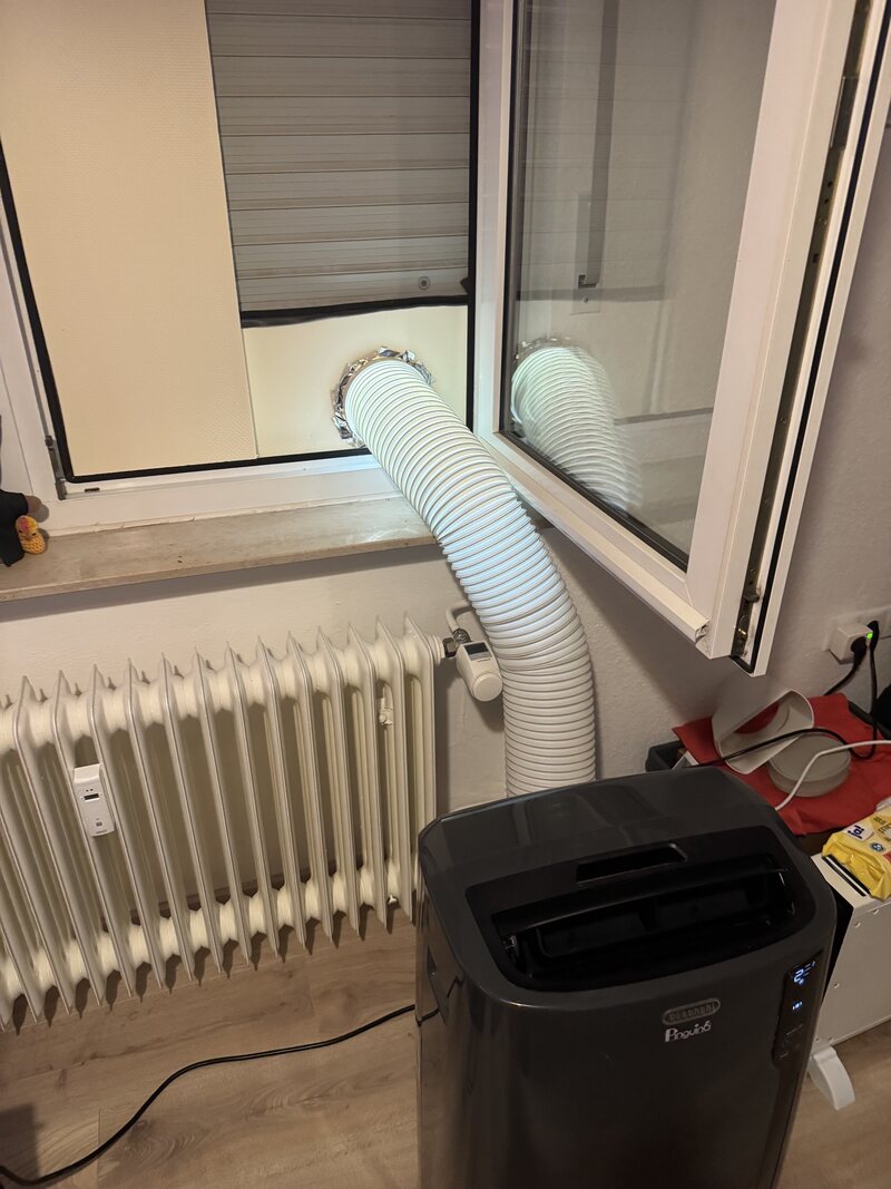 Portable air conditioner with the exhaust hose routed up to a tilted window