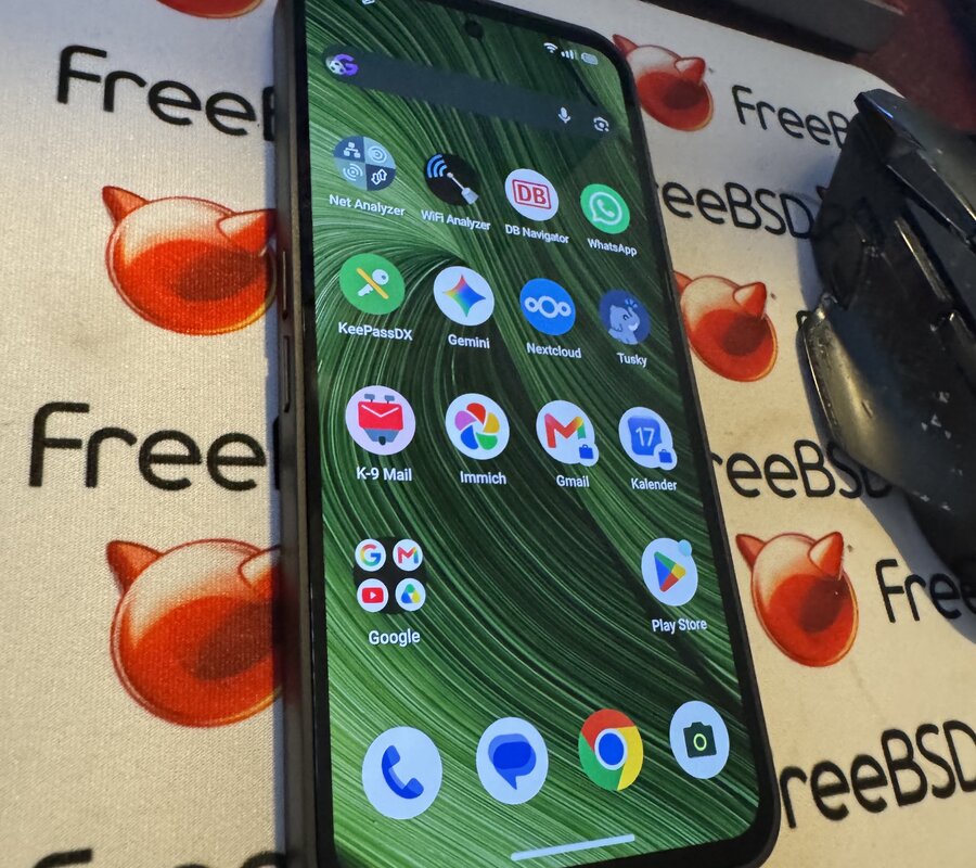 A Fairphone Gen6 standing on a FreeBSD Beastie mousepad, its home screen showing Nextcloud, Immich, Tusky, K-9 Mail and KeePassDX
